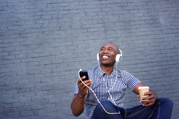 Sonriente hombre afroamericano escuchando música en auriculares