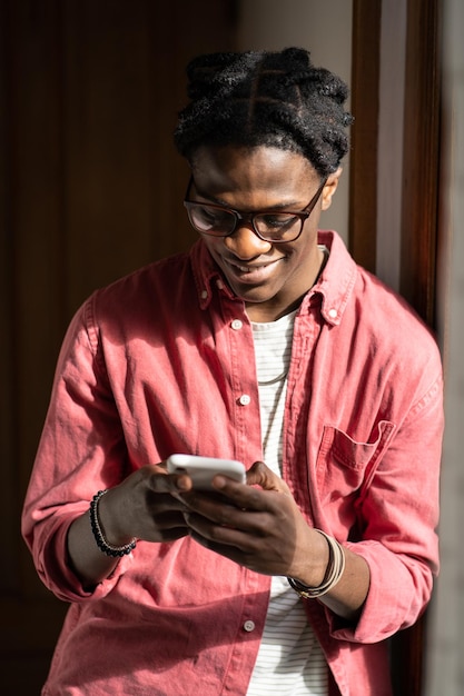 Sonriente hombre afroamericano feliz de pie en el interior regocijándose leyendo comentarios positivos en el blog wn