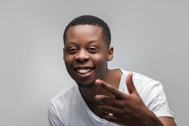 Sonriente hombre afroamericano lleno de alegría Felicidad risa buena suerte standup comic Headshot retrato sobre fondo gris con espacio libre