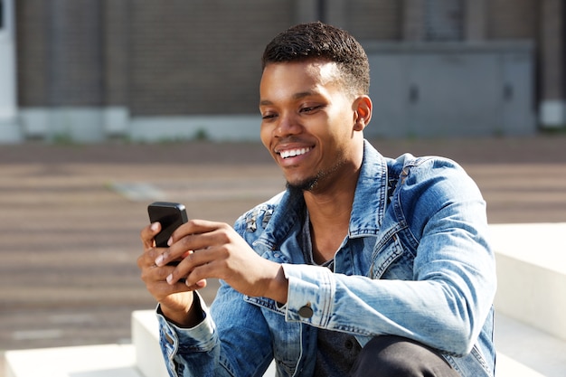 Sonriente hombre afroamericano con teléfono inteligente