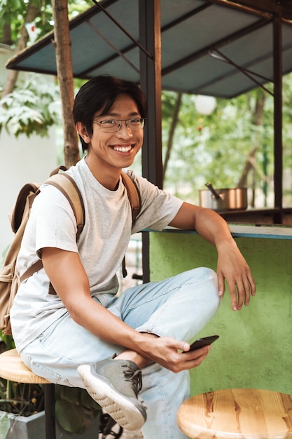 Sonriente hombre asiático estudiante con mochila