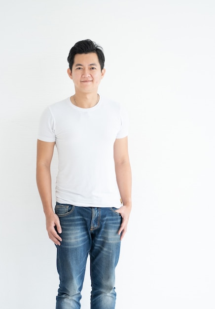 Sonriente hombre asiático guapo en camiseta blanca casual con jeans mirando a la cámara foto de estudio aislado sobre fondo blanco.