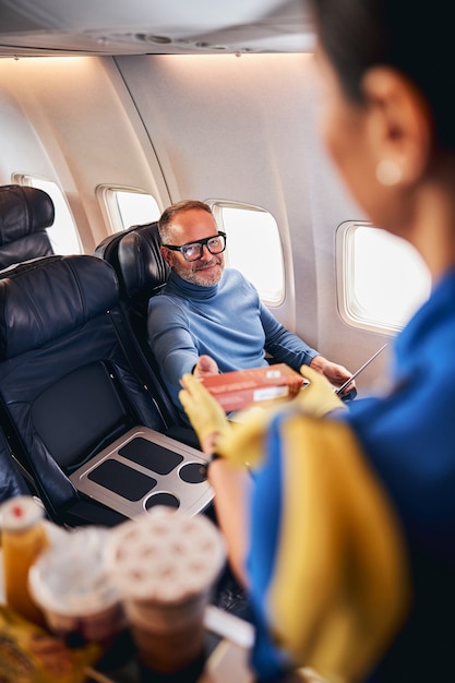 Sonriente hombre complacido de recibir la comida de la aerolínea