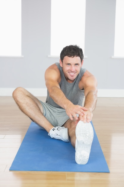 Sonriente hombre deportivo estirando su pierna derecha