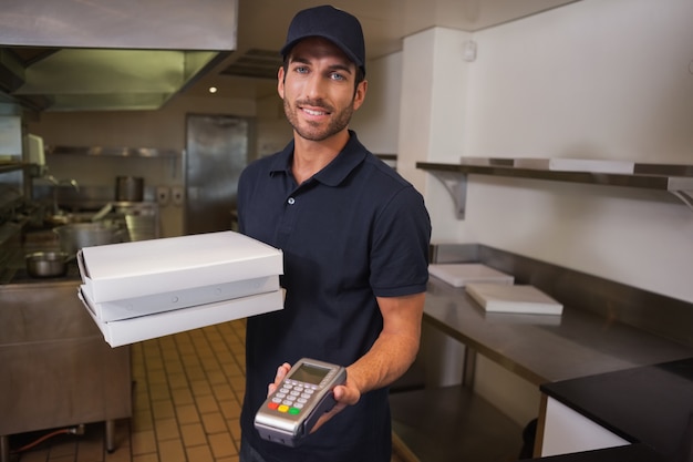 Sonriente hombre de entrega de pizza con tarjeta de crédito