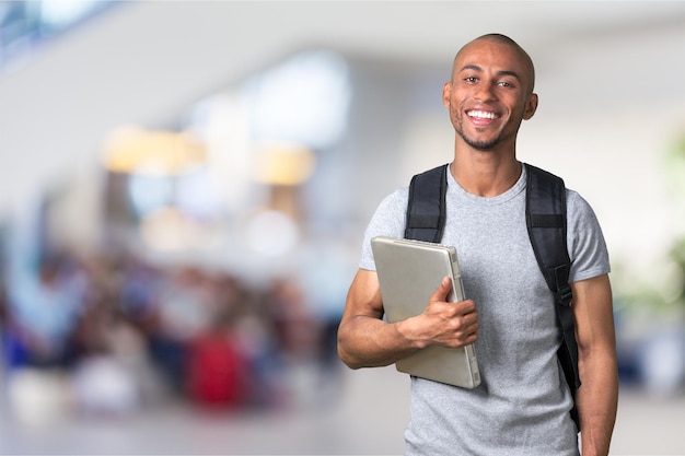 Sonriente hombre estudiante africano con laptop