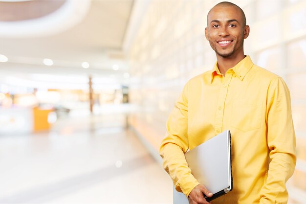 Sonriente hombre estudiante africano con portátil