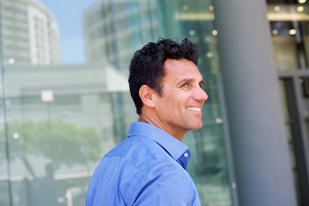 Sonriente hombre guapo caminando afuera en la ciudad