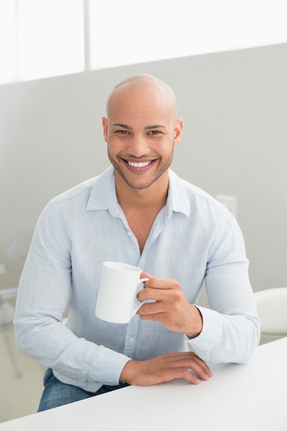 Sonriente hombre guapo con taza de café en casa