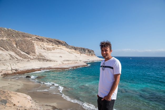 Sonriente hombre indio en una hermosa playa tropical con agua clara durante un fantástico día de verano, es feliz y disfruta de la vida.