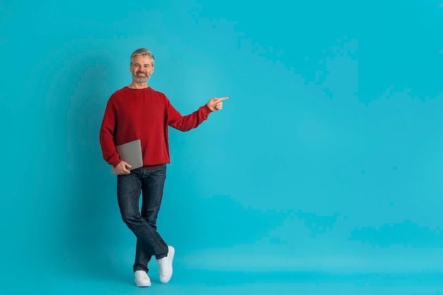 Sonriente hombre de mediana edad con laptop mostrando espacio vacío