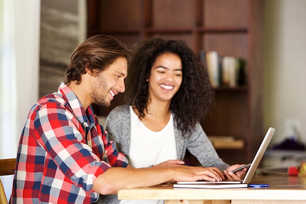 Foto sonriente hombre y mujer que trabaja con la computadora portátil