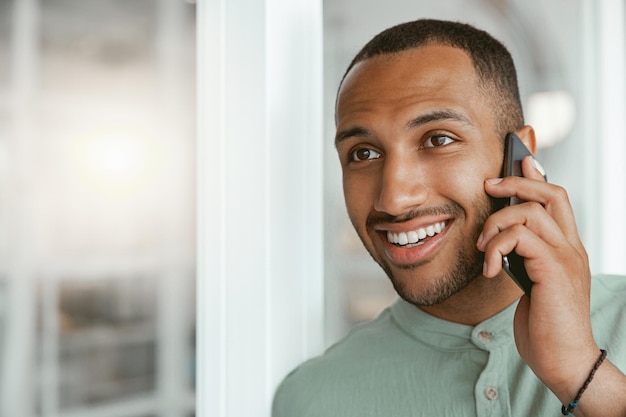 Sonriente hombre de negocios africano hablando por teléfono con el cliente mientras está en la oficina