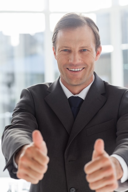 Sonriente hombre de negocios confía dando pulgares arriba