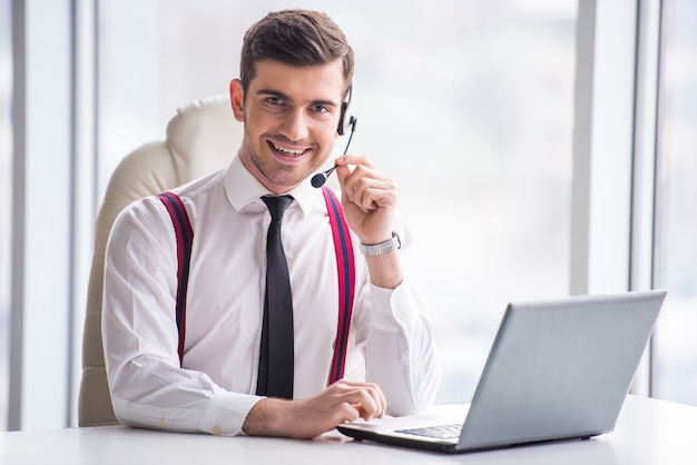 Sonriente hombre de negocios está tomando una llamada en un auricular.