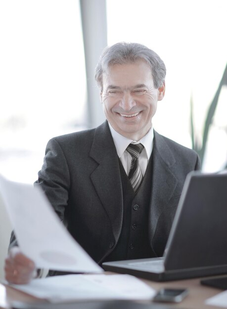 Sonriente hombre de negocios senior sentado en su escritorio