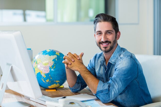 Sonriente hombre de negocios sentado en su escritorio