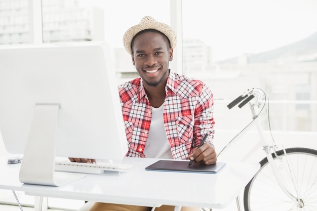 Sonriente hombre de negocios en sombrero de paja con digitalizador