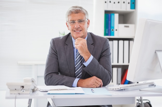 Sonriente hombre de negocios en su escritorio