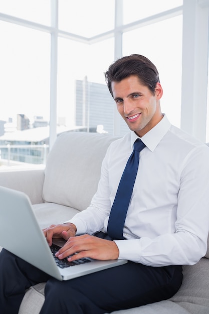 Sonriente hombre de negocios usando laptop