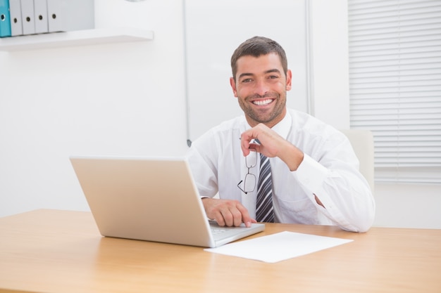 Sonriente hombre de negocios usando su computadora en su escritorio