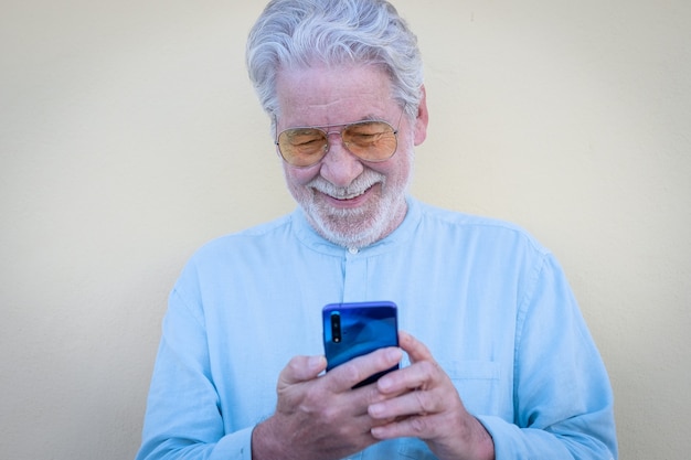 Sonriente hombre de pelo blanco senior mediante teléfono móvil en videollamada etired personas disfrutando de la tecnología