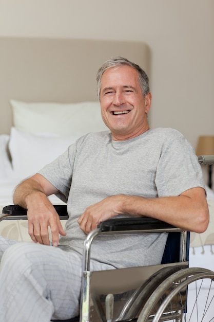 Sonriente hombre senior en su silla de ruedas en casa