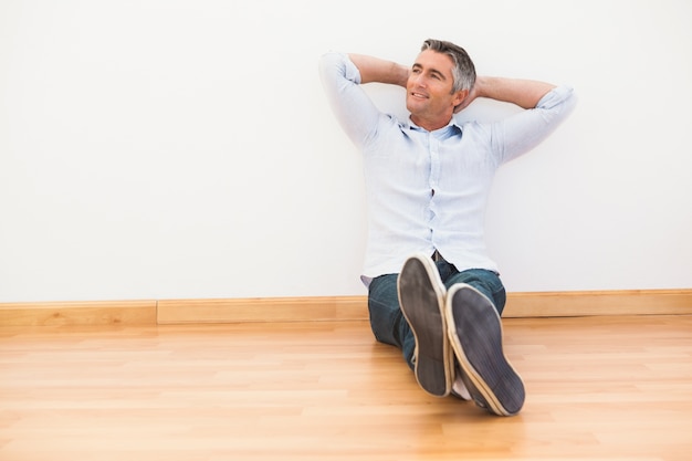 Sonriente hombre sentado en el parquet relajante