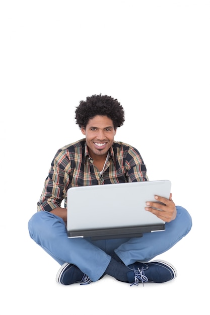 Sonriente hombre sentado y usando la computadora portátil