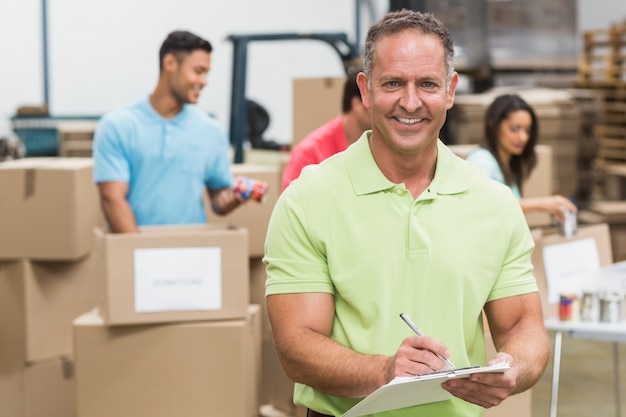 Sonriente hombre voluntario tomando notas sosteniendo portapapeles