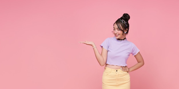 Sonriente joven adolescente asiática buscando y presentando mostrando lugar para su texto publicitario