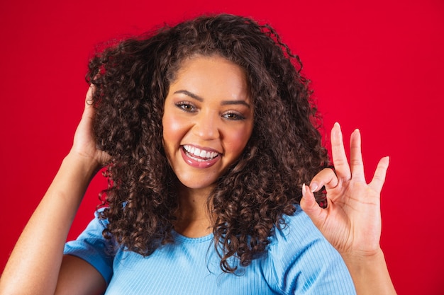 Sonriente joven afro haciendo el signo de ok.