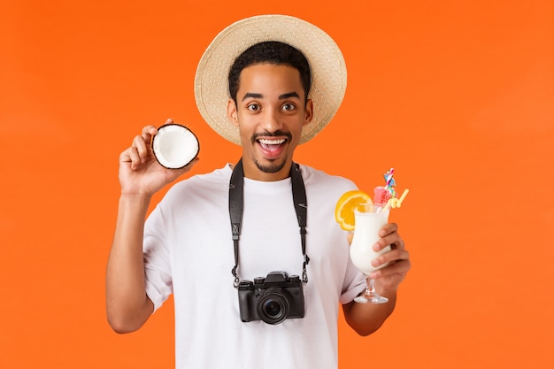 sonriente joven afroamericano con coco y cóctel