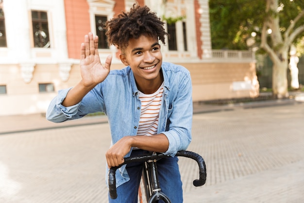 Sonriente joven afuera, montando en bicicleta