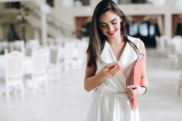 Sonriente joven anfitriona navegación smartphone