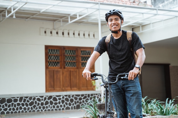 Sonriente joven asiática de pie con bicicleta plegable