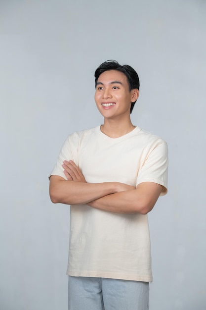 Sonriente joven asiático con los brazos cruzados sobre un fondo blanco.