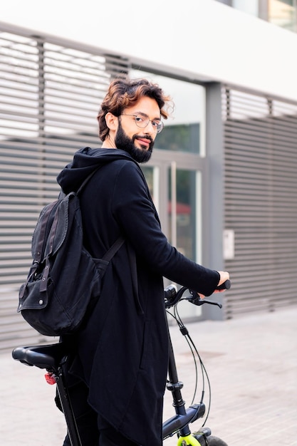 Sonriente joven caminando con una bicicleta plegable