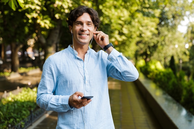 Sonriente joven casual sosteniendo teléfono móvil