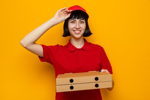 Sonriente joven caucásica repartidora sosteniendo cajas de pizza