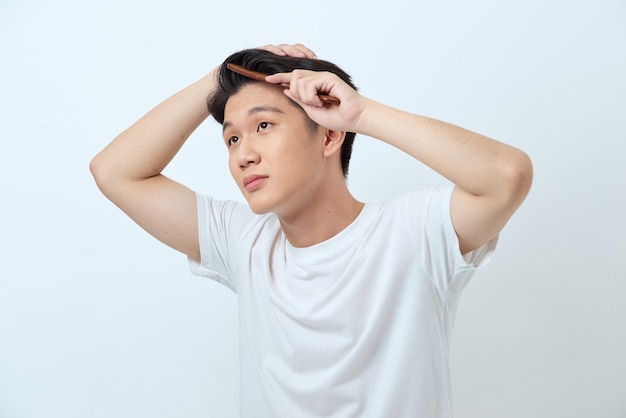 Sonriente joven cepillarse el cabello con un peine