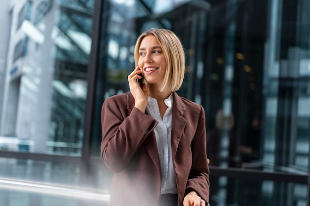 Sonriente joven empresaria en el teléfono en la ciudad