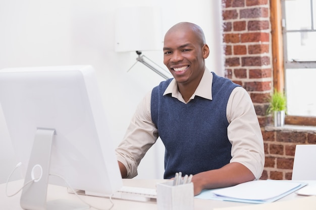 Sonriente joven empresario con la computadora en el escritorio