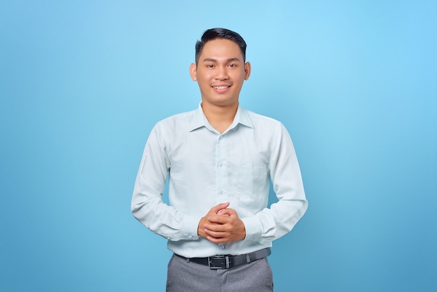 Sonriente joven empresario guapo cogidos de la mano con un rostro confiado sobre fondo azul.