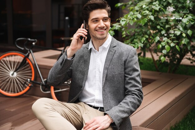 Sonriente joven empresario hablando por teléfono moible