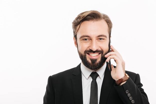 Sonriente joven empresario hablando por teléfono móvil.