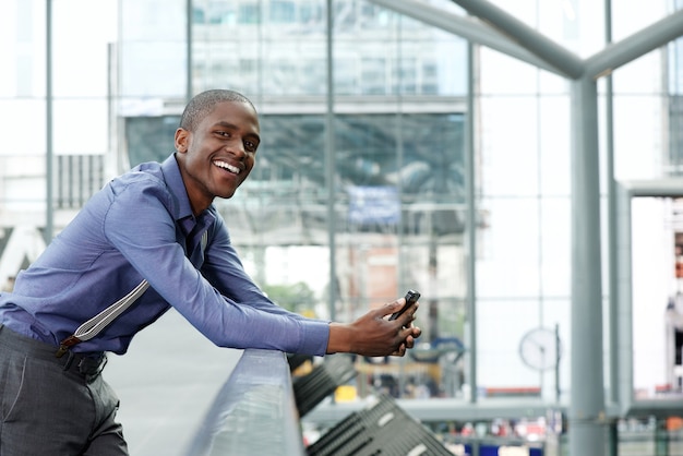 sonriente joven empresario negro con teléfono móvil