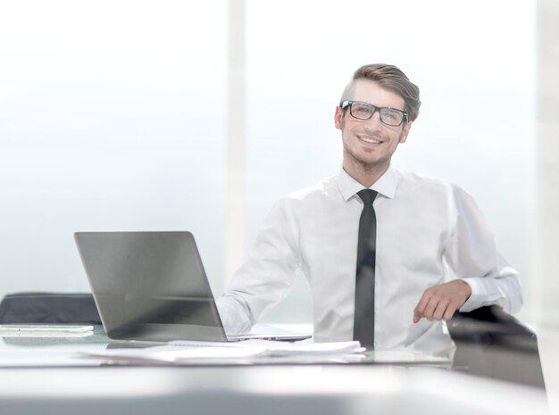 Sonriente joven empresario sentado en una espaciosa oficina