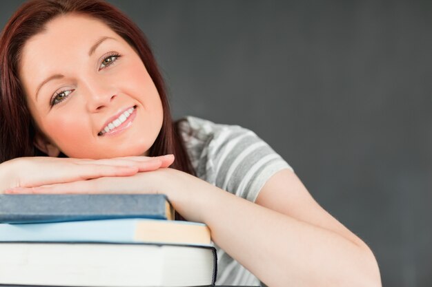 Sonriente joven estudiante se apoyó en sus libros