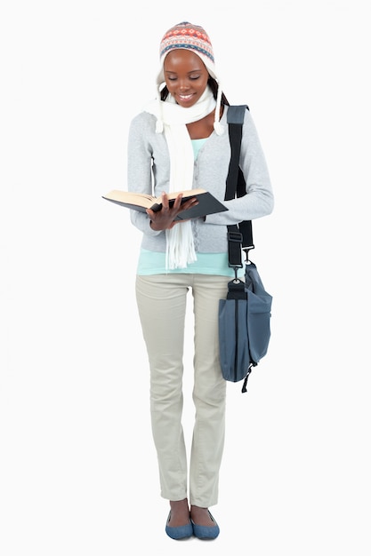 Sonriente joven estudiante leyendo un libro